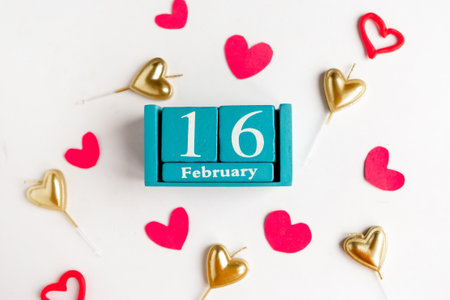 February 16. Blue cube calendar with month and date and decorative hearts on white background.の写真素材