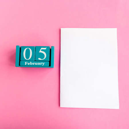 February 5. Blue cube calendar with month and date and white mockup blank on pink background.の写真素材