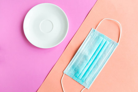 medical mask and empty plate on color background. Minimal concept.