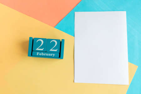 February 22. Blue cube calendar with month and date and white mockup blank on color geometric background.の写真素材