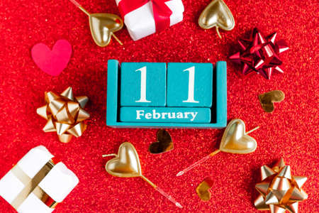 February 11. Blue cube calendar with month and date and decorations on red glitter background.の写真素材