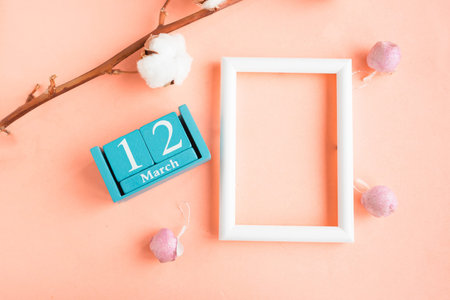 March 12. Blue cube calendar with month and date and mockup photo frame on pink pastel background.