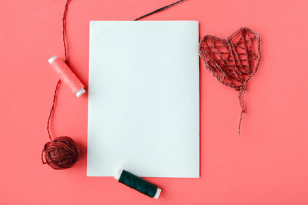 Thread handmade heart and white mockup blank on pink background, copy space for the text