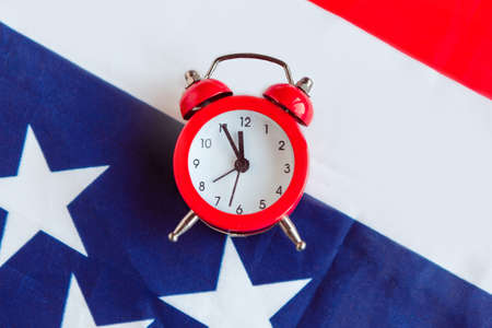 Alarm clock on American flag background. Minimal concept, top viewの写真素材