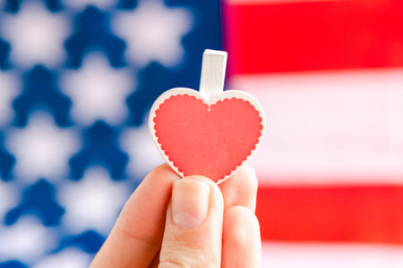 Woman's hand holds red heart over USA flag. National love concept