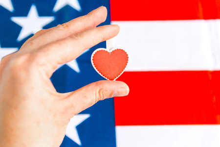 Woman's hand holds red heart over USA flag. National love conceptの写真素材