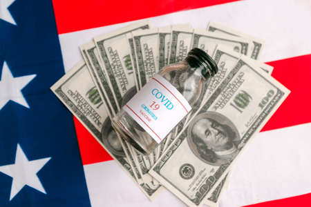 Covid-19 vaccine and dollars on American flag. Economic US crisis in coronavirus contextの写真素材