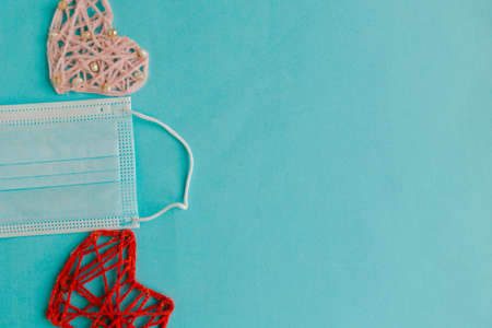 Two knitted hearts and medical mask on blue background. Valentine's Day during the pandemic. Happy Valentine's Day 2021. Copy space for the textの写真素材