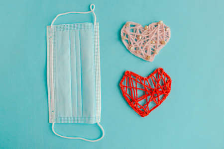 Two knitted hearts and medical mask on blue background. Valentine's Day during the coronavirus pandemic. Happy Valentine's Day 2021の写真素材