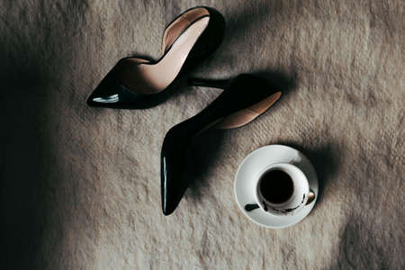 Flat lay photo with classic high-heeled shoes and half-finished coffee on the bedの写真素材
