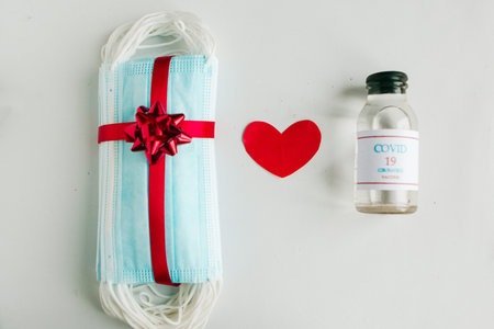Stack of medical masks with gift bow on white background. Valentine's Day during the coronavirus pandemic.の写真素材