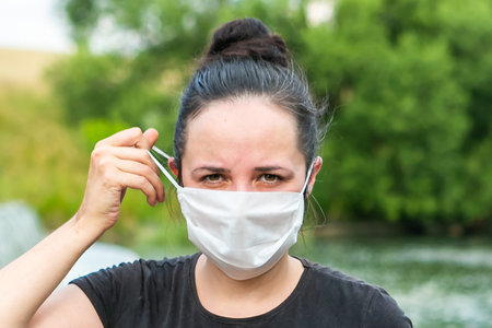 Woman taking off protective mask from her face during the coronavirus outbreak, coronavirus free...