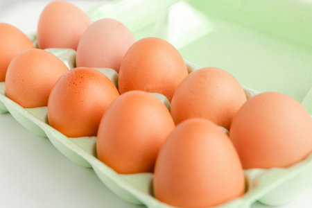 Closeup photo of raw chicken eggs in egg box. food background.