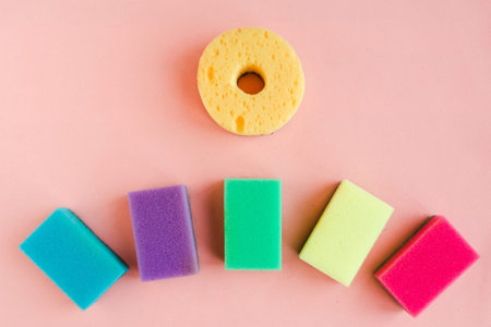Multicolor sponges for washing dishes on pink background. minimal concept.