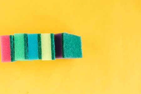 Stack of multicolor sponges for washing dishes on bright yellow background. minimal concept. Copy space for the textの写真素材