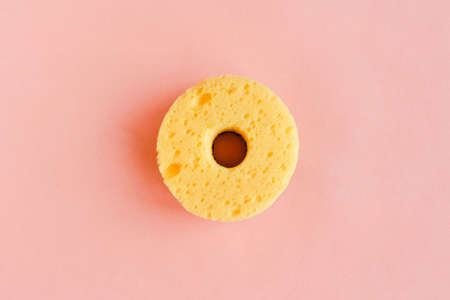 Round yellow sponge for washing dishes on pink background. Minimal conceptの写真素材