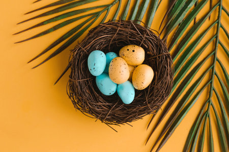 Color quail eggs in the nest and palm branch on orange background. easter holiday concept