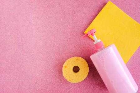 Bottle with pink dish washing liquid and sponges for washing on pink glitter background. copy spaceの写真素材