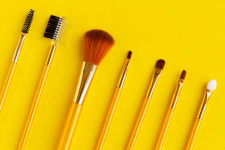 Set of different cosmetic makeup brushes on bright yellow background.の写真素材