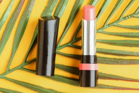 Pink lipstick on bright yellow background flat lay top view minimal. Beauty and cosmetics background. Decorative cosmetics, makeup, women's lipstick, beauty brand, product designの写真素材