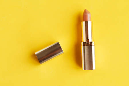 Pink lipstick on bright yellow background flat lay top view minimal. Beauty and cosmetics background. Decorative cosmetics, makeup, women's lipstick, beauty brand, product designの写真素材