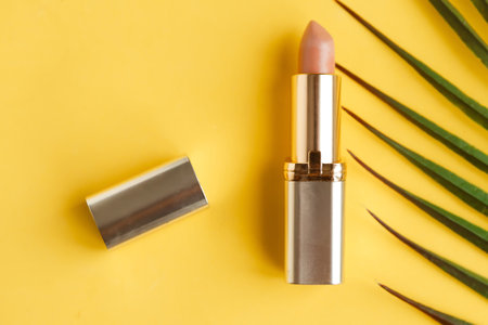 Pink lipstick on bright yellow background flat lay top view minimal. Beauty and cosmetics background. Decorative cosmetics, makeup, women's lipstick, beauty brand, product designの写真素材