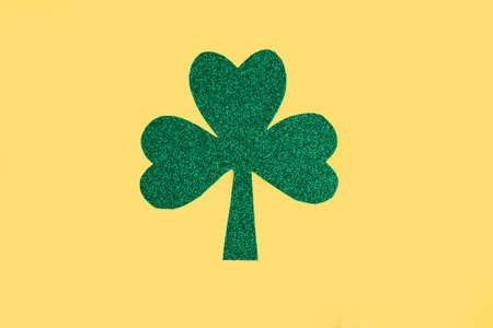 Green shamrock isolated on bright yellow background. Three leaf clover, top view. minimal concept. Symbol of St. Patrick's Dayの写真素材