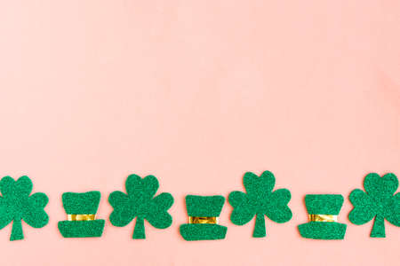 St. Patrick's Day side border shamrocks and leprechaun hats on pastel pink background. Copy space for the textの写真素材