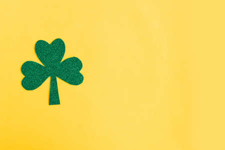 Green shamrock isolated on bright yellow background. Three leaf clover, top view. Minimal concept. Symbol of St. Patrick's Day. Copy space for the textの写真素材