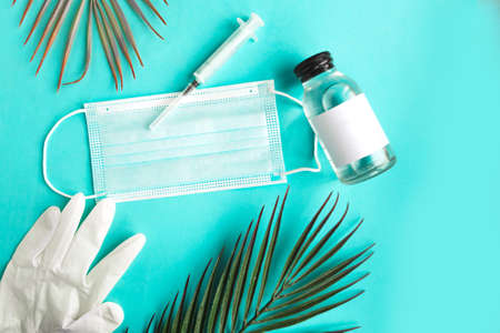 Face medical mask, hand sanitizer and palm three leaf on green mint background. Coronavirus holiday conceptの写真素材