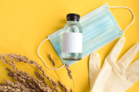 Face medical mask, hand sanitizer bottle and gloves on bright yellow background. Summer holidays during the coronavirus pandemic concept. Corona holidays.の写真素材
