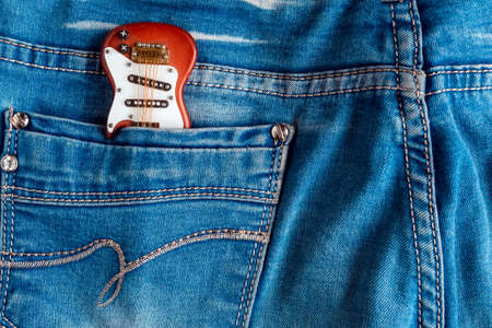 Toy electric guitar in the jeans back pocket. View of musician from the backの写真素材