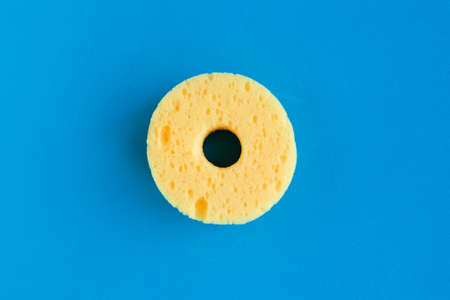 Round yellow sponge for washing dishes on blue background. minimal conceptの写真素材