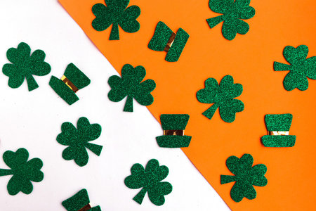 Happy St. Patrick's Day. Shamrocks and leprechaun hats pattern on white and orange background....