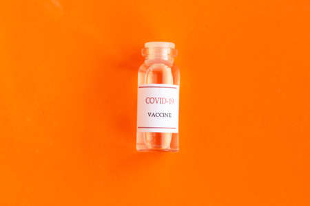 Coronavirus vaccine bottle on bright orange background. Minimal conceptの写真素材