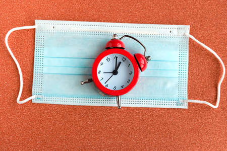 Alarm clock and face medical mask on green glitter background. Minimal conceptの写真素材