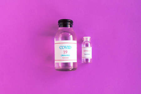 Coronavirus vaccine bottle on bright purple background. Minimal conceptの写真素材