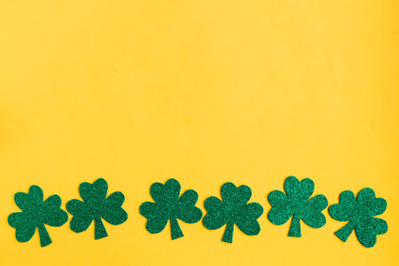 St. Patrick's Day low border paper shamrocks on yellow background. Copy space for the textの写真素材