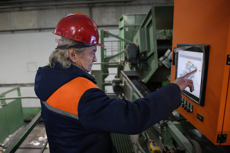 Minsk Belarus â€“ February 14 2021: machine operator wearing hardhat standing at control panel...