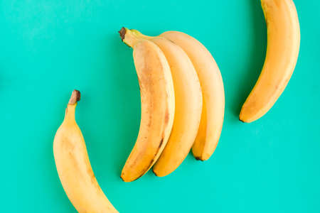 Fresh tasty yellow bananas on green mint background. Healthy food concept. minimal conceptの写真素材