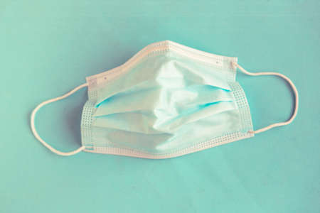 Face medical mask on pastel blue background. Top view, minimalの写真素材