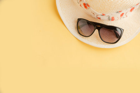 Straw hat and sunglasses on yellow background. Top view. Travel concept. Copy space