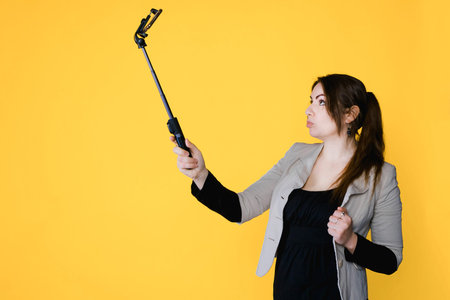 Woman do selfie in studio with yellow isolated background. Copy space