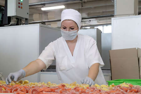 Minsk Belarus - February 2 2021: confectionery factory. A woman sorts marmalade on a conveyor beltのeditorial素材