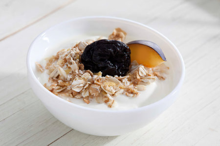 Bowl of yogurt with muesli and plum
