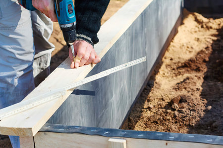 Gardener screwing on wooden plank to build a raised bed