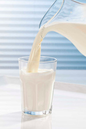 milk being poured into glass, close upの写真素材