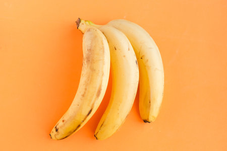 Fresh tasty bananas on orange backgroundの写真素材