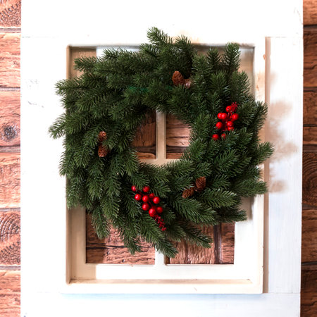 Decorative Christmas wreath in white frame on wooden wallの写真素材