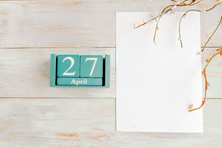 April 27. Blue cube calendar with month and date and white mockup blank on wooden backgroundの写真素材